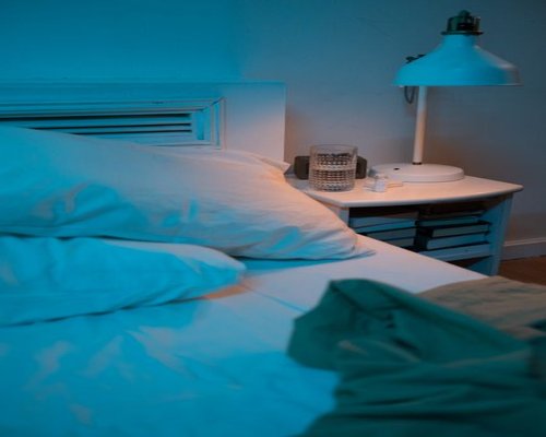 A dimly lit bedroom corner showing a book resting closed on a bedside nightstand preparing for sleep