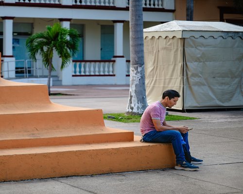 A person taking a brief pause looking away from a phone on a sunny terrace in Mexico